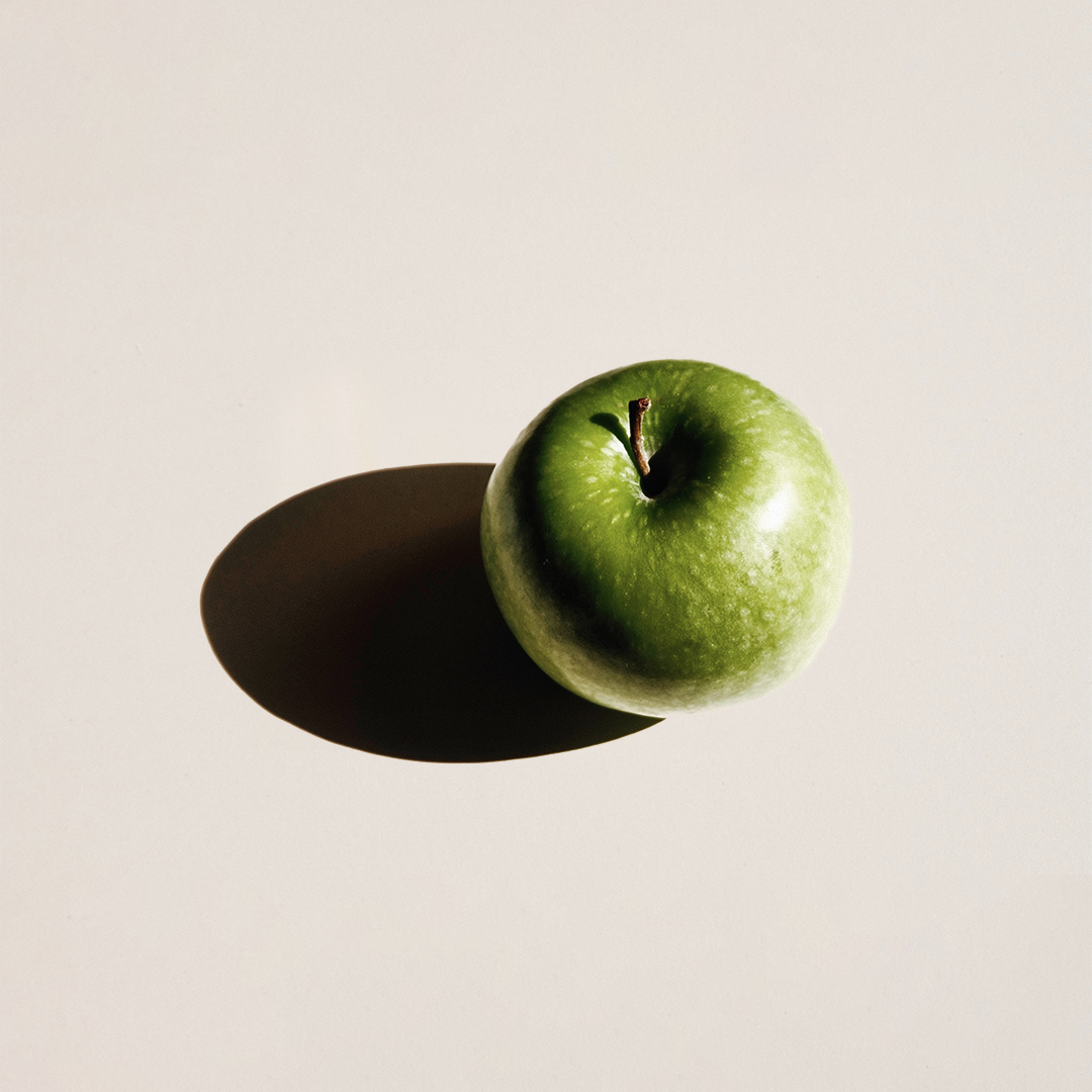 A green apple with a shadow on the left