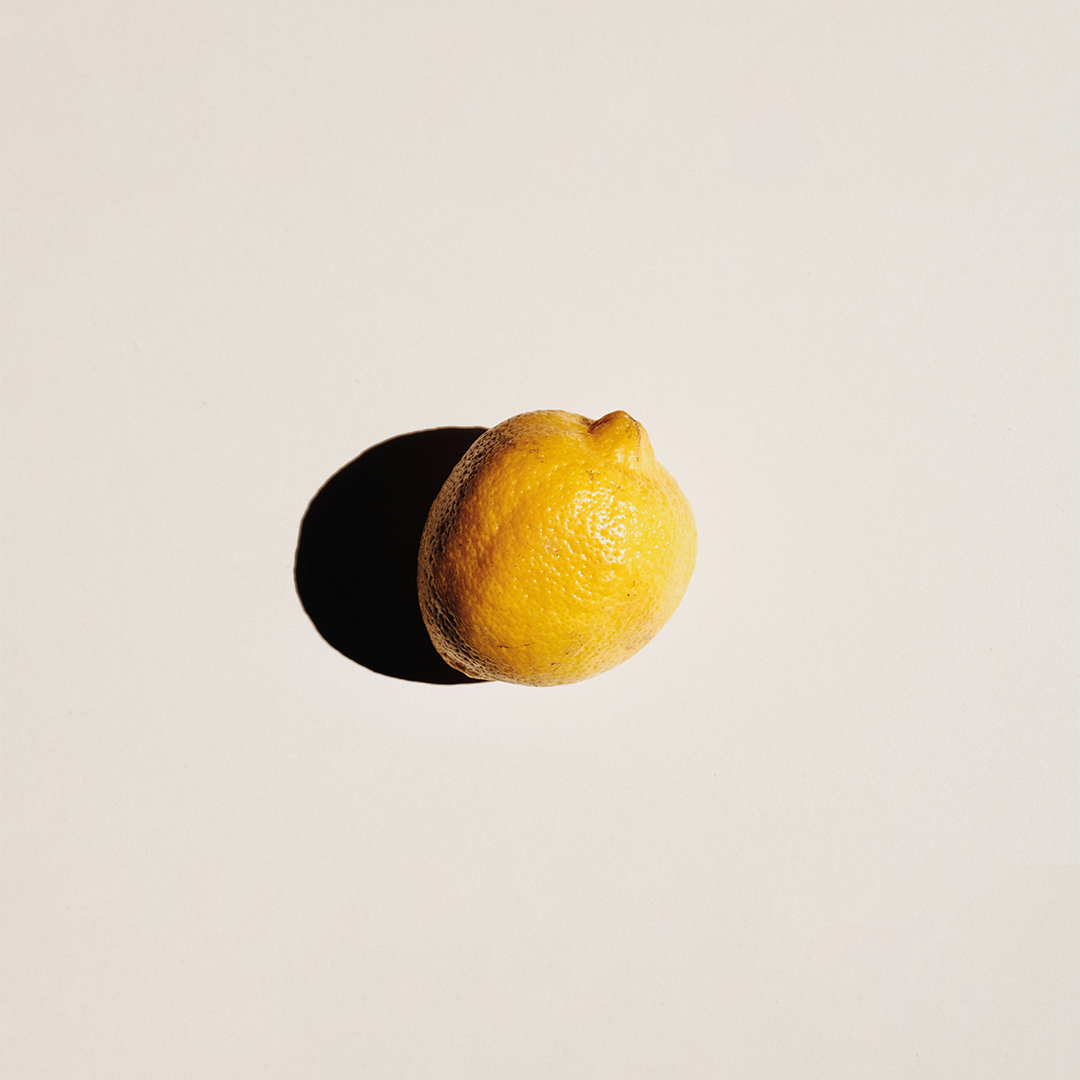 A yellow lemon with a shadow on the left